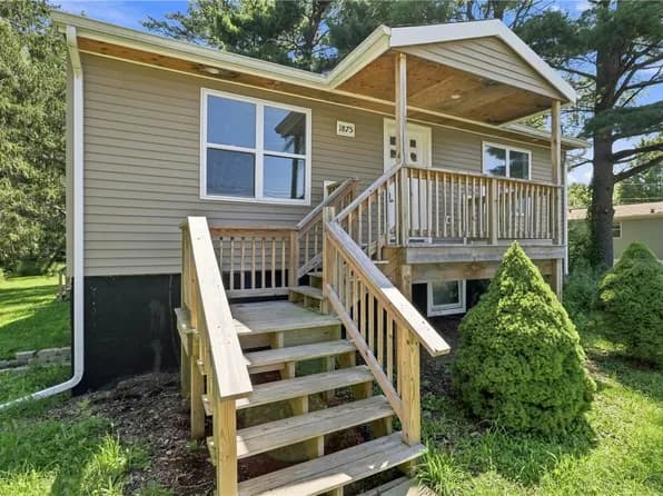 Raised ranch home with covered porch and wooden steps